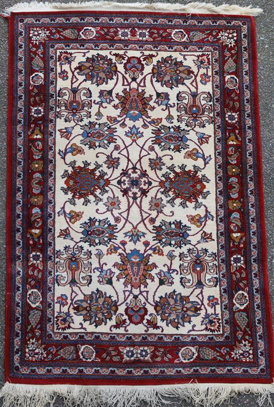 A Persian cream ground rug with central field of foliate motifs